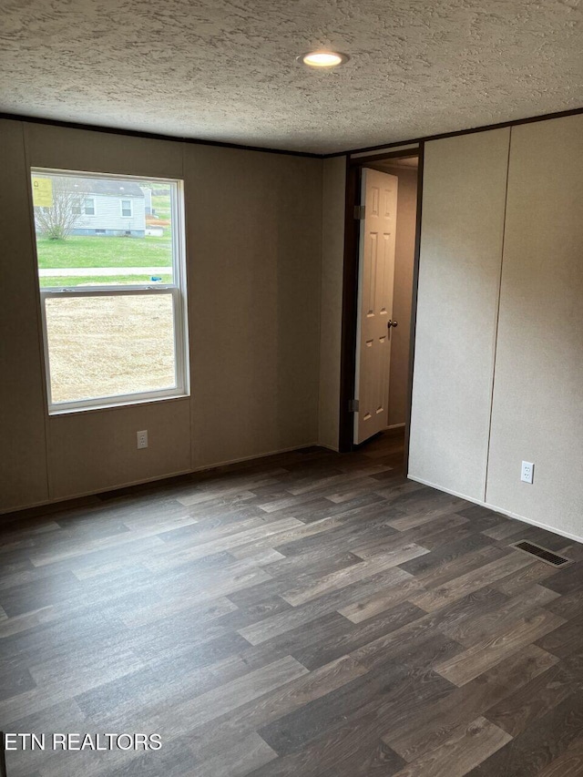 unfurnished room featuring dark wood-type flooring and a textured ceiling