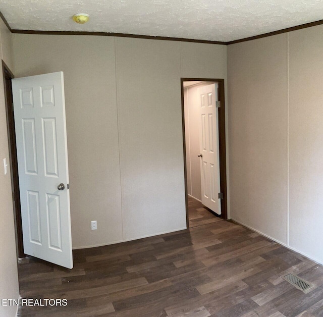 unfurnished bedroom featuring visible vents, wood finished floors, ornamental molding, and a textured ceiling