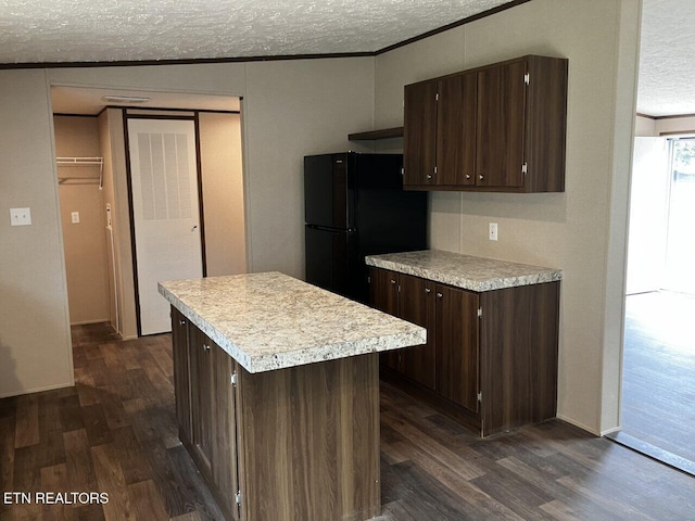 kitchen featuring light countertops, dark brown cabinetry, freestanding refrigerator, a textured ceiling, and dark wood-type flooring