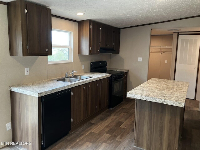 kitchen featuring dark wood-style flooring, light countertops, under cabinet range hood, a sink, and black appliances