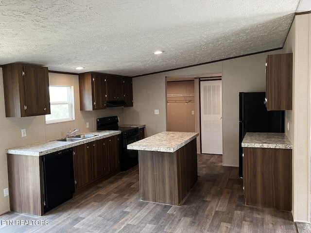 kitchen with light countertops, a sink, a kitchen island, black appliances, and dark wood-style flooring