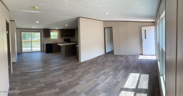 unfurnished living room featuring recessed lighting, dark wood-type flooring, crown molding, and a textured ceiling