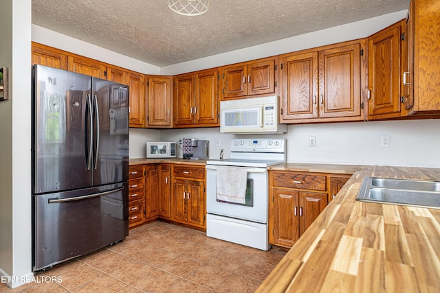709 Head Of Creek Rd, Sweetwater, TN 37874 - kitchen with white appliances, butcher block countertops, brown cabinets, light tile patterned floors, and a textured ceiling