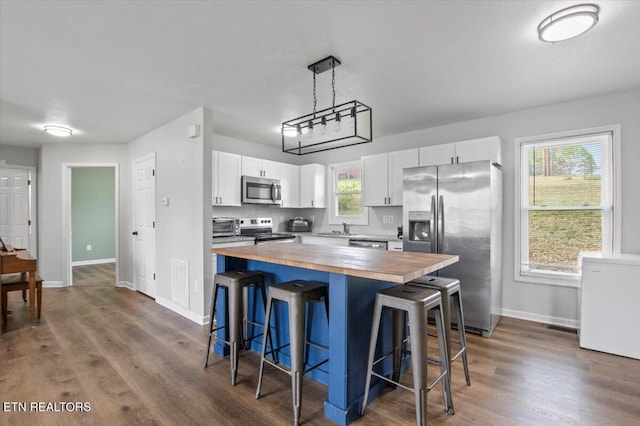 174 Sandy Hill Rd, Lafollette, TN 37766 - kitchen with dark wood-style floors, a kitchen bar, white cabinets, appliances with stainless steel finishes, and butcher block counters