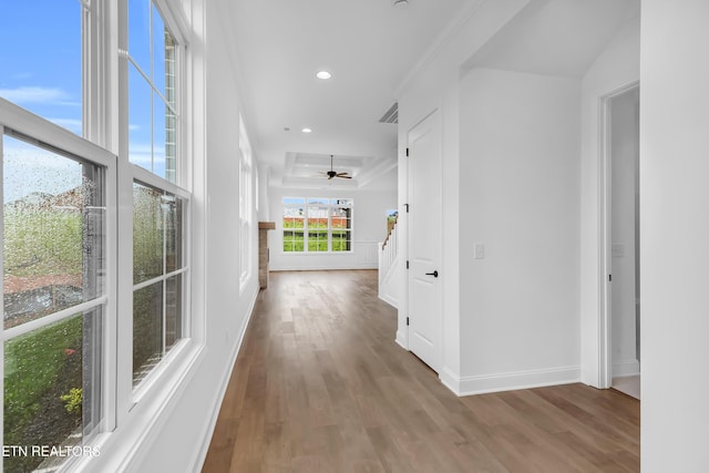 hall featuring baseboards, a tray ceiling, recessed lighting, and wood finished floors