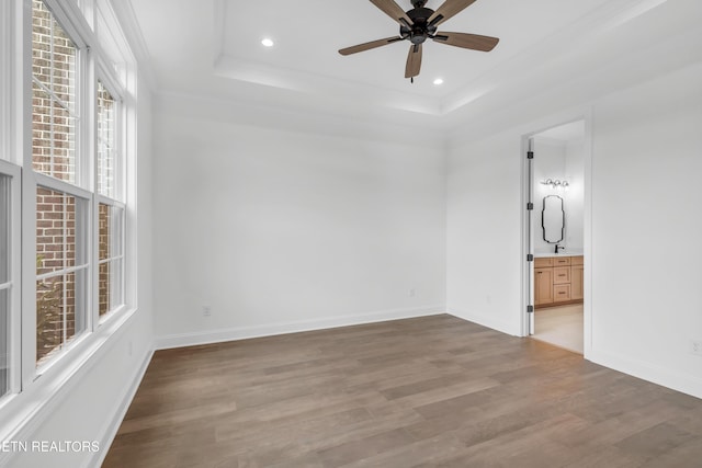 unfurnished bedroom with a tray ceiling, crown molding, baseboards, light wood-style floors, and recessed lighting