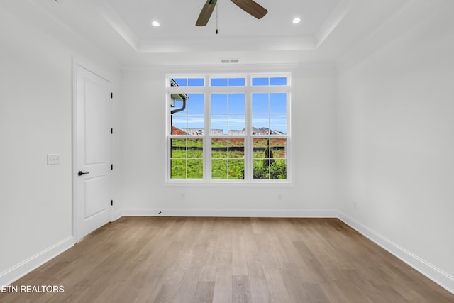 empty room featuring visible vents, a tray ceiling, ceiling fan, and wood finished floors