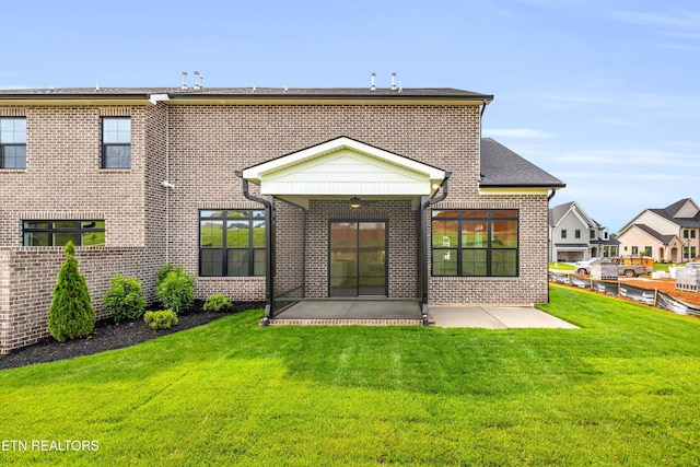 rear view of house with a patio, brick siding, and a lawn