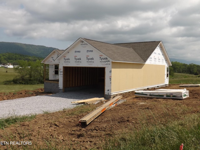 152 Nevils St, Harrogate, TN 37752 - view of front of house with an attached garage, gravel driveway, a shingled roof, a mountain view, and an outbuilding