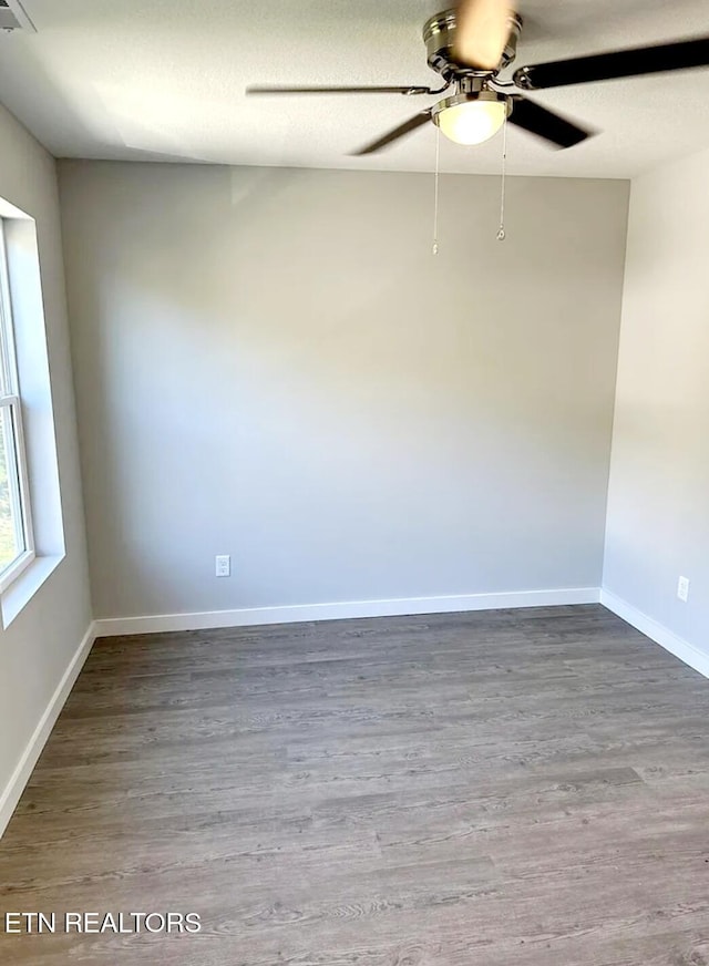 spare room featuring a textured ceiling, baseboards, wood finished floors, and a ceiling fan