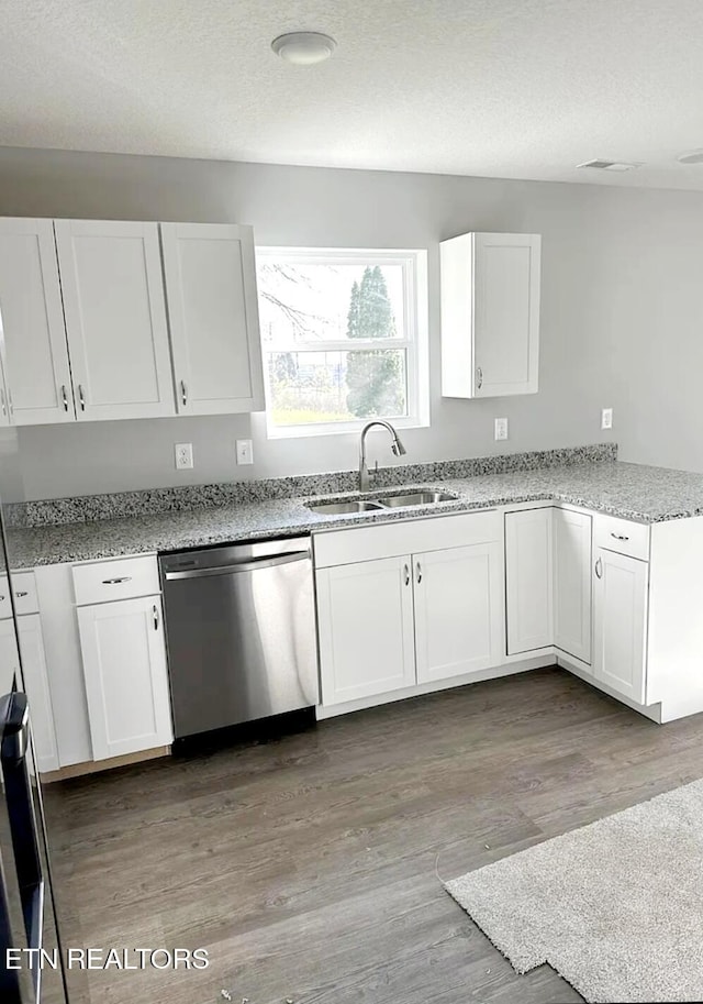 kitchen with a sink, light stone countertops, wood finished floors, stainless steel dishwasher, and white cabinets