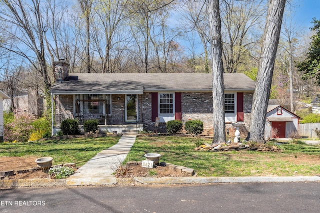 ranch-style house with a chimney, a front yard, brick siding, a porch, and a shed