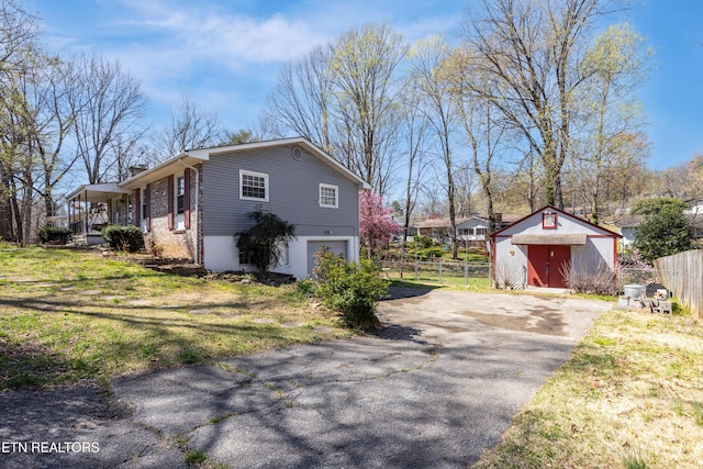 view of home's exterior with driveway, a shed, an outbuilding, fence, and a yard