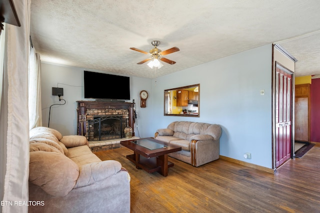 living area featuring a textured ceiling, ceiling fan, wood finished floors, and a fireplace