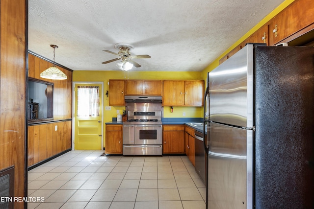 kitchen featuring light tile patterned flooring, brown cabinets, under cabinet range hood, stainless steel appliances, and ceiling fan