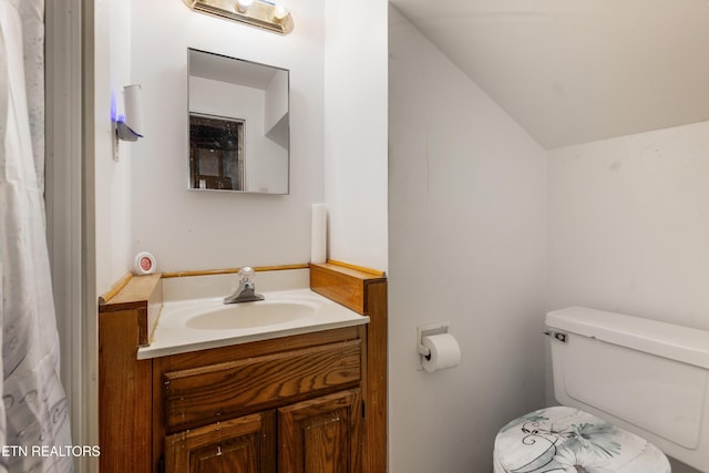 half bathroom featuring lofted ceiling, toilet, and vanity