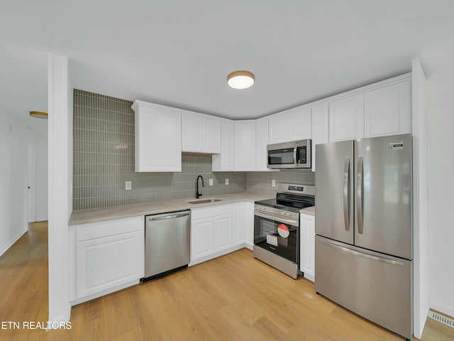 2249 Knollcrest Ln, Knoxville, TN 37920 - kitchen featuring light countertops, light wood finished floors, stainless steel appliances, a sink, and backsplash