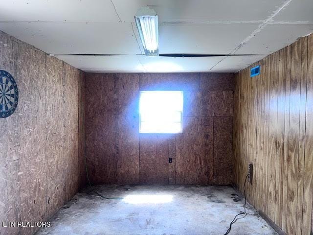 spare room featuring unfinished concrete flooring and wooden walls