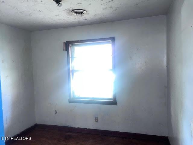 unfurnished room with visible vents and wood finished floors