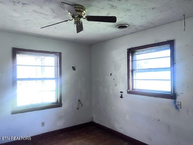 spare room featuring baseboards, a textured ceiling, and a ceiling fan