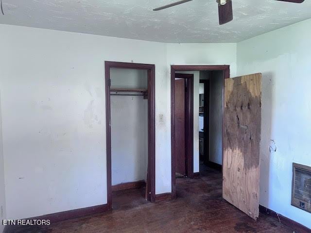 unfurnished bedroom with baseboards, a textured ceiling, heating unit, a ceiling fan, and a closet