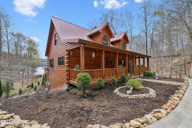 view of front of house with log siding, metal roof, and a porch