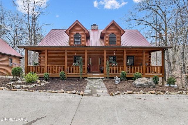 cabin with metal roof, a chimney, covered porch, and log exterior