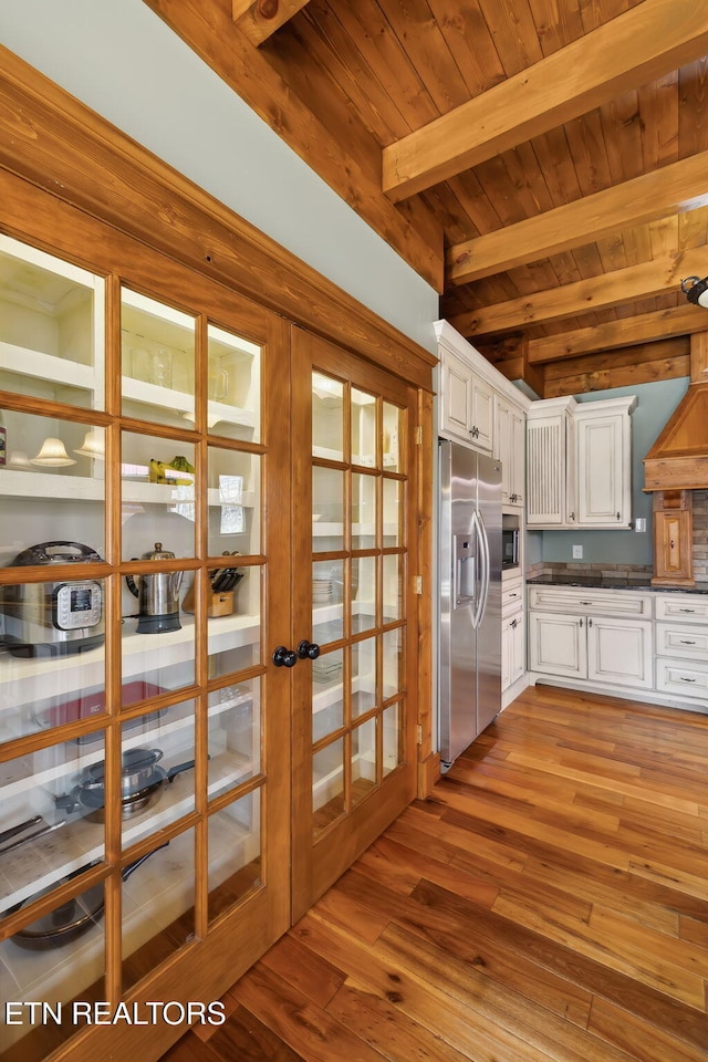 kitchen featuring white cabinetry, french doors, stainless steel appliances, beam ceiling, and wood finished floors
