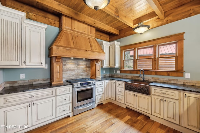 kitchen with light wood-style flooring, stainless steel range with gas cooktop, a sink, custom range hood, and wood ceiling