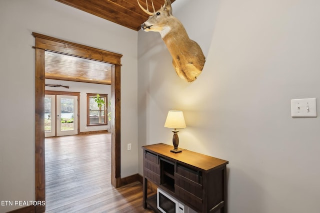 hallway featuring baseboards, wood finished floors, and wood ceiling