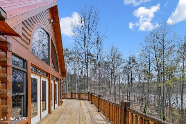 wooden terrace featuring french doors and a view of trees