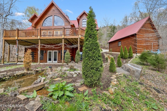 rear view of property featuring metal roof, a wooden deck, french doors, and log exterior