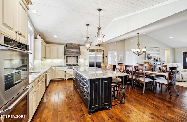 8207 Washington Pike, Corryton, TN 37721 - kitchen with a kitchen breakfast bar, premium range hood, dark cabinetry, stainless steel appliances, and cream cabinetry