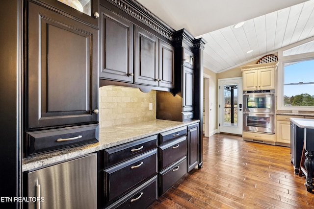 8207 Washington Pike, Corryton, TN 37721 - kitchen featuring stainless steel double oven, lofted ceiling, wood-type flooring, backsplash, and light stone counters