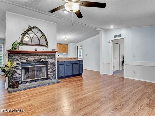 unfurnished living room with light wood-style flooring, a textured ceiling, a ceiling fan, visible vents, and lofted ceiling