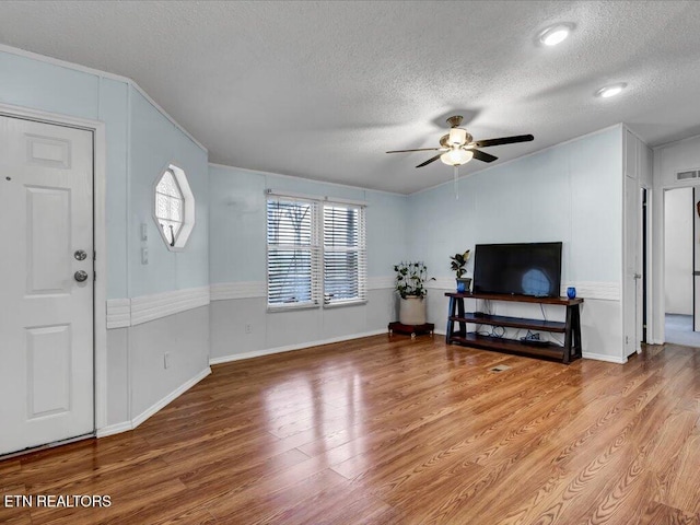 foyer entrance with light wood-style flooring, a textured ceiling, and ceiling fan