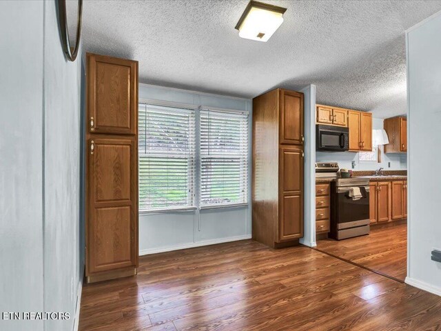 kitchen with stainless steel range with electric stovetop, dark wood-type flooring, black microwave, and a textured ceiling