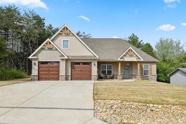 craftsman-style house with stone siding, driveway, and a front lawn