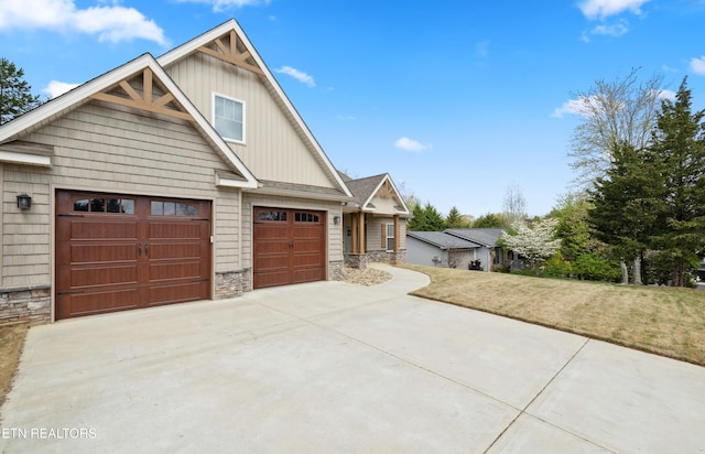 craftsman-style house with board and batten siding, stone siding, driveway, a garage, and a front yard