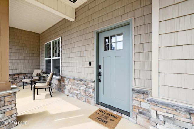 property entrance with stone siding and a porch