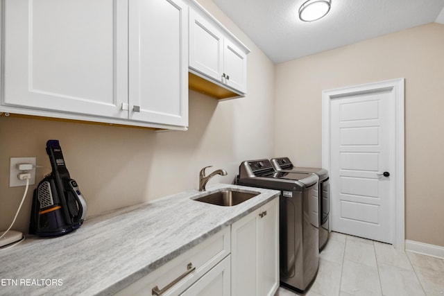 laundry area featuring separate washer and dryer, cabinet space, baseboards, and light tile patterned floors