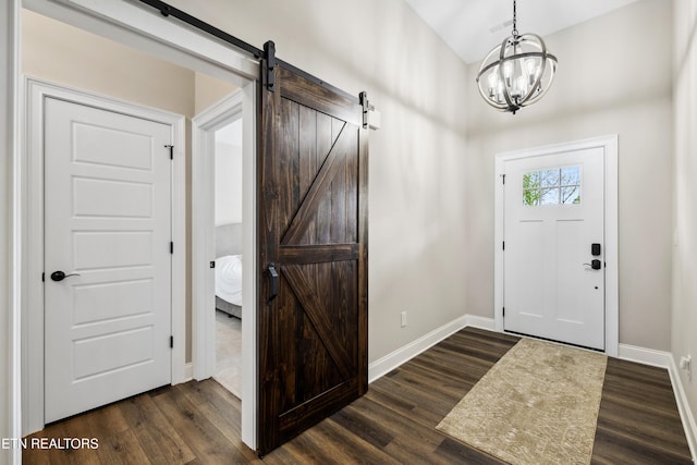 foyer featuring baseboards, dark wood-style floors, a chandelier, and a barn door