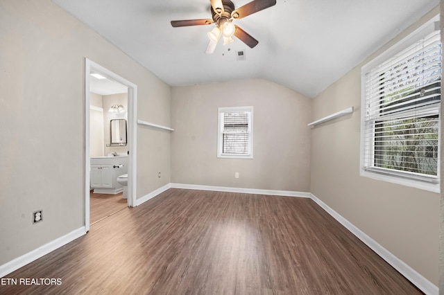 unfurnished bedroom with baseboards, lofted ceiling, wood finished floors, and multiple windows