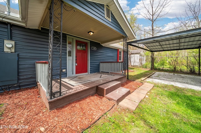 property entrance featuring driveway, a carport, covered porch, and fence