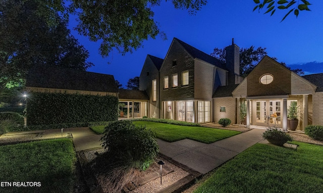 11901 S Fox Den Dr, Knoxville, TN 37934 - back of house at night with french doors, a lawn, a chimney, and brick siding