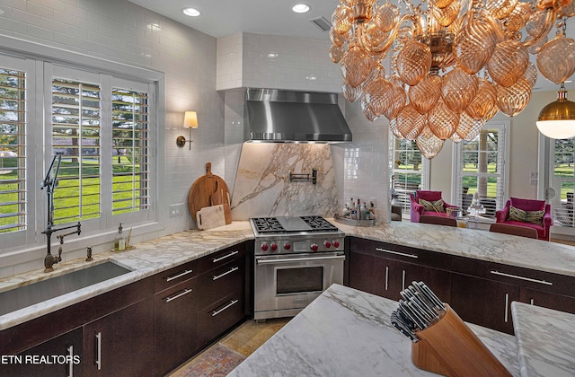 11901 S Fox Den Dr, Knoxville, TN 37934 - kitchen featuring premium stove, wall chimney exhaust hood, a chandelier, decorative backsplash, and dark brown cabinetry
