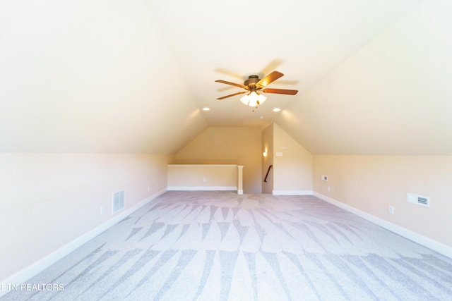 additional living space featuring baseboards, visible vents, light colored carpet, and lofted ceiling