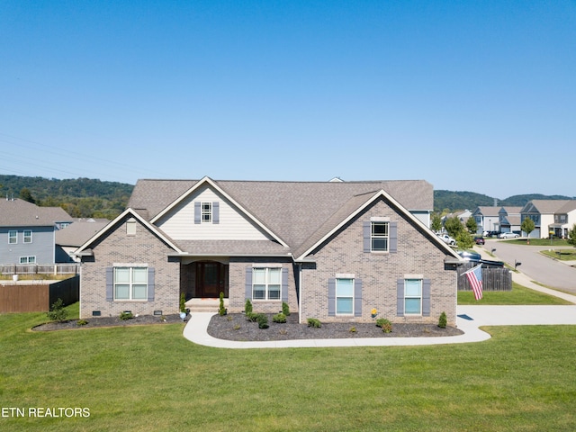 view of front of home with brick siding, fence, a front lawn, and roof with shingles