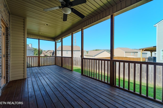 unfurnished sunroom featuring a residential view and ceiling fan