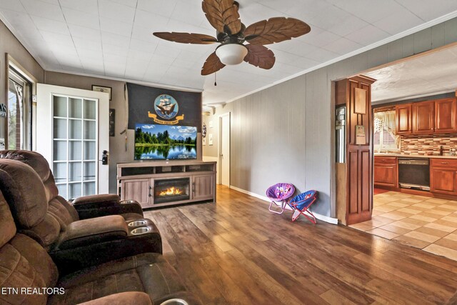 107 Ford St, Byrdstown, TN 38549 - living room with crown molding, baseboards, light wood-style floors, ceiling fan, and a warm lit fireplace